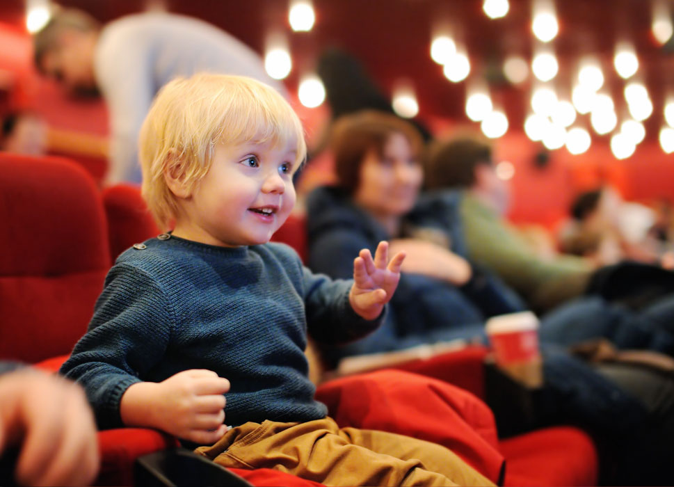 Kleiner fröhlicher blonder Junger als Zuschauer im Theater